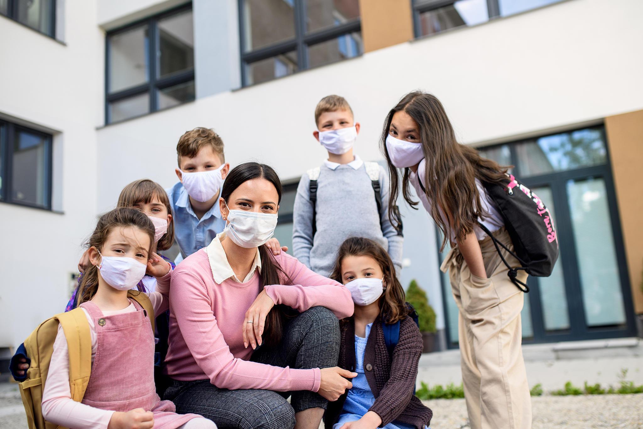 Elementary school teacher and her students wearing COVID-19 masks